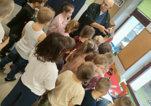 Przedszkolaki oglądają wystawę elementów kultury japońskiej, podczas gdy p. Dariusz omawia poszczególne przedmioty.