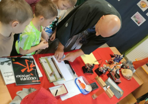 Pan Dariusz Szpakowski wręcza dzieciom stempelki z japońskimi znakami.