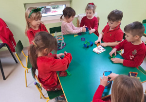 "Żabki" przy stole bawią się klockami magnetycznymi.