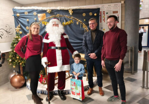 Odbiór nagrody za zwycięstwo w kategorii A - Jaś wraz z Rodzicami, Świętym Mikołajem i p. Burmistrzem Miasta Ozorkowa - p. Jackiem Sochą na tle dekoracji mikołajkowej na Pływalni "Wodnik" w Ozorkowie.