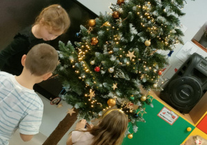 Ubieramy choinkę na pniu, wykorzystując kolorowe, plastikowe bombki o różnej wielkości.