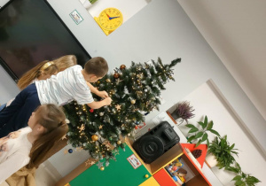 Ubieramy choinkę na pniu, wykorzystując kolorowe, plastikowe bombki o różnej wielkości.