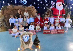 Dzieci i ciocie z grupy "Wiewiórki" pozują do zdjęcia z Mikołajem, który dał im prezenty