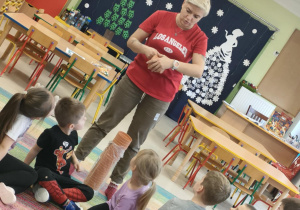 Pani Anna Kowalczyk tłumaczy dzieciom, jak należy wykonać świąteczny dzwoneczek.