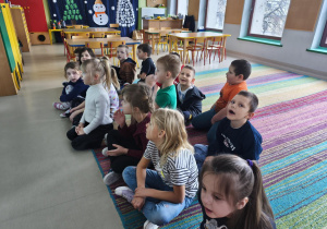 Dzieci oglądają film edukacyjny o rukoli na ekranie multimedialnym.