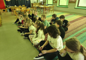 Dzieci siedzą przed ekranem i odpowiadają w ciszy na pytanie, czym jest starość.