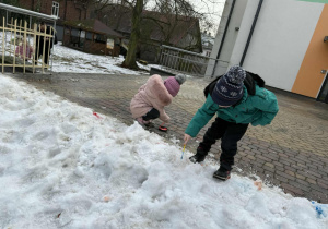 Kilkoro dzieci z grupy "Żabek" maluje śnieg za pomocą farby i pędzelków.