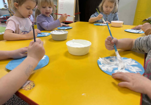 Dzieci malują śnieżynki z wykorzystaniem przygotowanej farby.