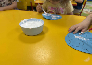 Dzieci malują śnieżynki z wykorzystaniem przygotowanej farby.
