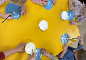 Dzieci malują śnieżynki z wykorzystaniem przygotowanej farby.