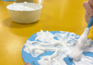 Dzieci malują śnieżynki z wykorzystaniem przygotowanej farby.