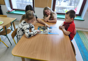 "Pszczółki" podczas pracy w grupie oglądają publikację pt. "Skąd się biorą produkty ekologiczne?"