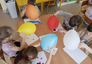 Kilkoro dzieci z grupy "Motylków", korzystając z kolorowych farb i balonów tworzy pracę plastyczną.