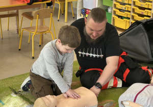 Dzieci z grupy "Motylków" kolejno uczą się uciskania klatki piersiowej na fantomie.