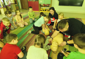 "Pszczółki" kolejno ćwiczą uciskanie klatki piersiowej na fantomie w obecności ratowników medycznych.