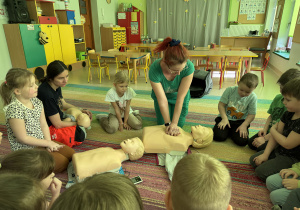 Nauczycielka grupy "Pszczółek" ćwiczy przebieg resuscytacji krążeniowo-oddechowej na fantomie.