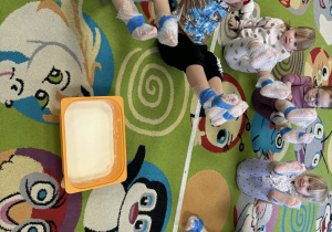 Dzieci prezentują swoje owinięte stopy w folię bąbelkową.