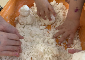 Dzieci lepią bałwanki ze sztucznego śniegu.