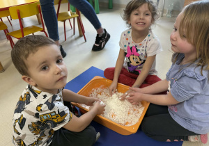 Dzieci lepią bałwanki ze sztucznego śniegu.