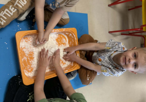 Dzieci lepią bałwanki ze sztucznego śniegu.
