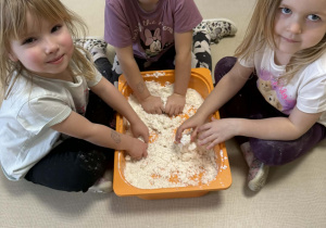 Dzieci lepią bałwanki ze sztucznego śniegu.