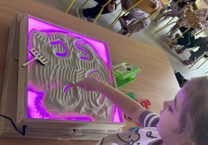 "Motylki" kolejno rysują w piasku, wykorzystując edukacyjną tablicę ze światłem led.