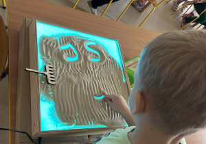 "Motylki" kolejno rysują w piasku, wykorzystując edukacyjną tablicę ze światłem led.