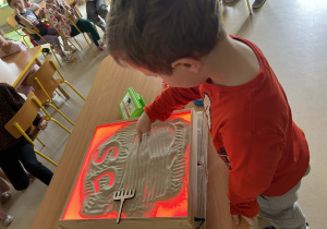 "Motylki" kolejno rysują w piasku, wykorzystując edukacyjną tablicę ze światłem led.