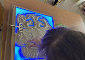"Motylki" kolejno rysują w piasku, wykorzystując edukacyjną tablicę ze światłem led.