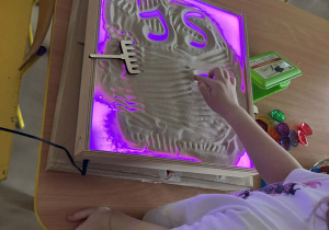 "Motylki" kolejno rysują w piasku, wykorzystując edukacyjną tablicę ze światłem led.