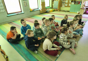 Dzieci oglądają film edukacyjny o dinozaurach na ekranie multimedialnym.