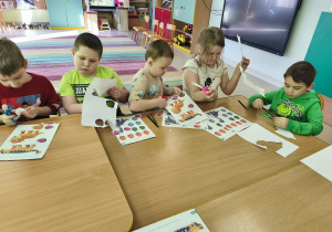 Przy połączonych stołach wycinamy szablony dinozaurów i ich jaj.