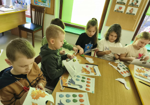 Przy połączonych stołach wycinamy szablony dinozaurów i ich jaj.