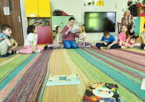 Pani Joanna Jaszczak recytuje nam wiersz pt. "Bajka o Bobrze Malarzu", autorstwa Moniki Dereniowskiej, a dzieci siedzą na dywanie i słuchają jego treści.