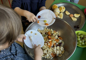 Dzieci wrzucają pokrojone owoce do miski.