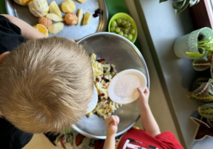 Dzieci wrzucają pokrojone owoce do miski.