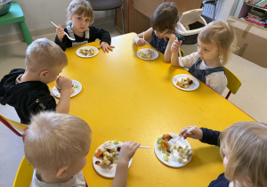 Dzieci jedzą przygotowana przez siebie sałatkę owocową.