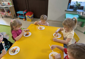 Dzieci jedzą przygotowana przez siebie sałatkę owocową.