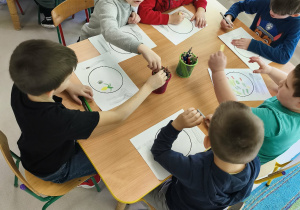 Kilkoro dzieci przy stole rysuje swój, zdrowy posiłek.