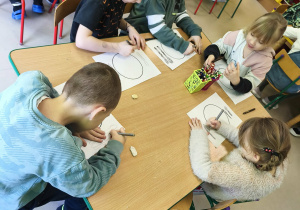 Kilkoro dzieci przy stole rysuje swój, zdrowy posiłek.