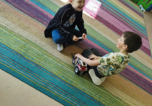 Chłopcy bawią się zabawkowym pojazdem.