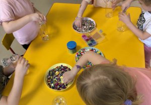 Dzieci wkładają do butelek wybrane ozdoby.
