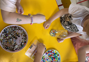 Dzieci wkładają do butelek wybrane ozdoby.