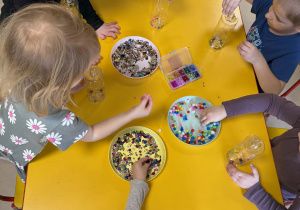 Dzieci wkładają do butelek wybrane ozdoby.