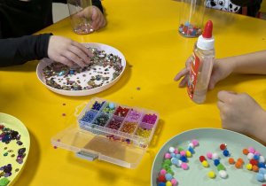 Dzieci wkładają do butelek wybrane ozdoby.