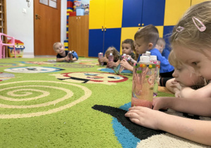 Dzieci oglądają przygotowane przez siebie butelki.