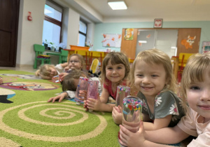 Dzieci oglądają przygotowane przez siebie butelki.