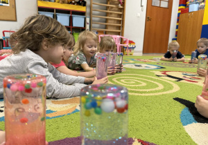 Dzieci oglądają przygotowane przez siebie butelki.