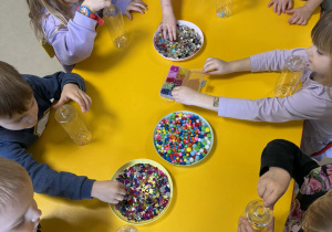 Dzieci wkładają do butelek wybrane ozdoby.