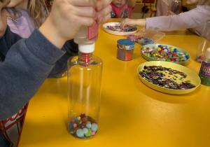 Dzieci wkładają do butelek wybrane ozdoby.